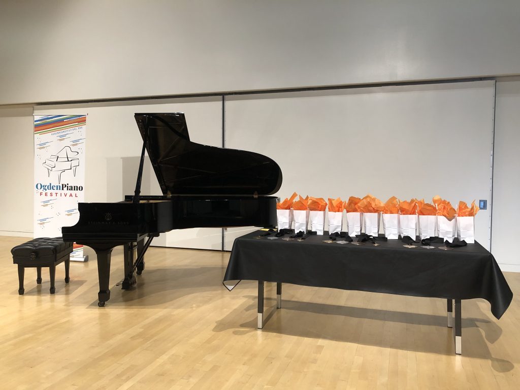 Black Steinway piano next to table with medals and prize bags awaiting the awards ceremony. 