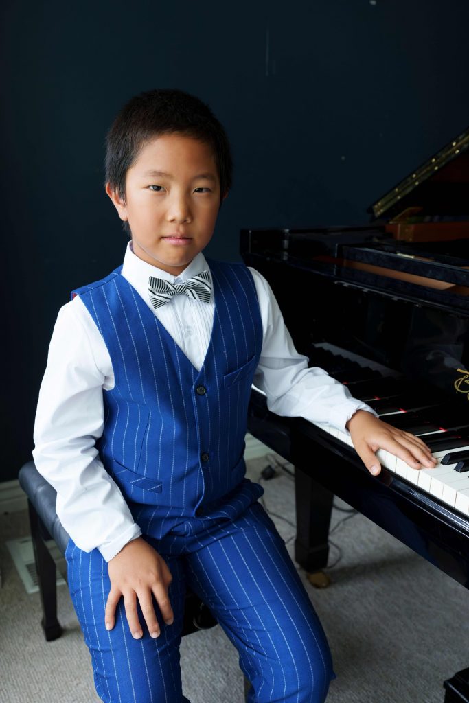 Pianist Maxwell Ji next to a grand piano