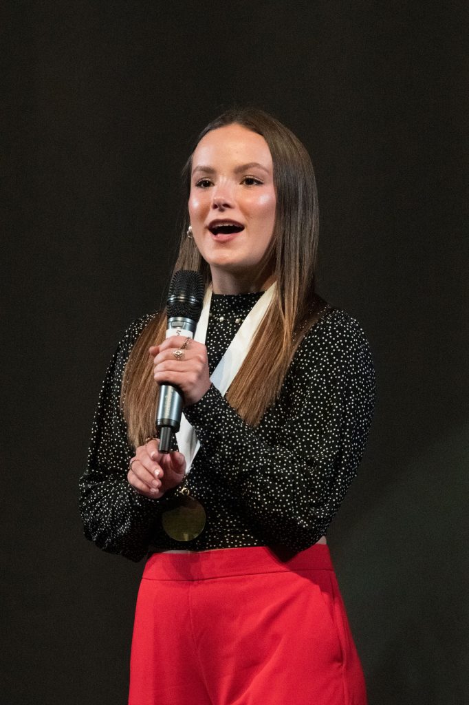 Genevieve Fullmer, Guest Speaker stands on stage.