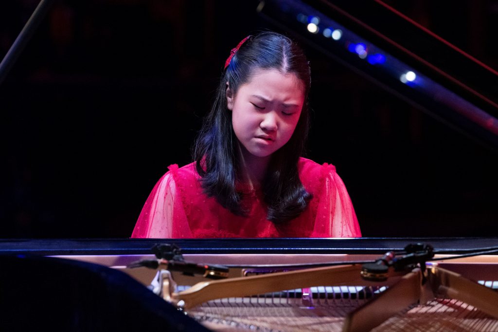 Christina Sung plays the piano. View is across the body of the piano with lid raised. 