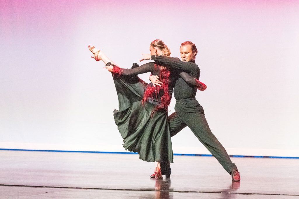 Annika dances with Tanner. Her left leg is raised in the air.