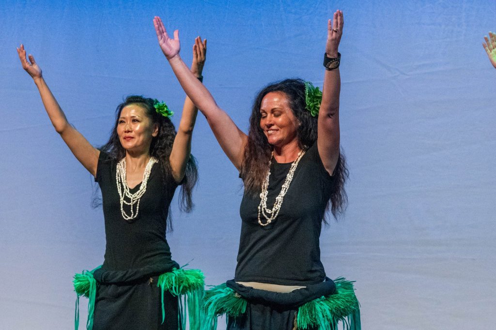 'Ori Tahiti dancer in green side skirts. Arms raised to the sky